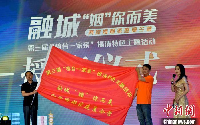 福清市旅台同胞亲属联谊会会长陈天鸿(左)将营旗授予到营员代表朱浚达。　张斌 摄