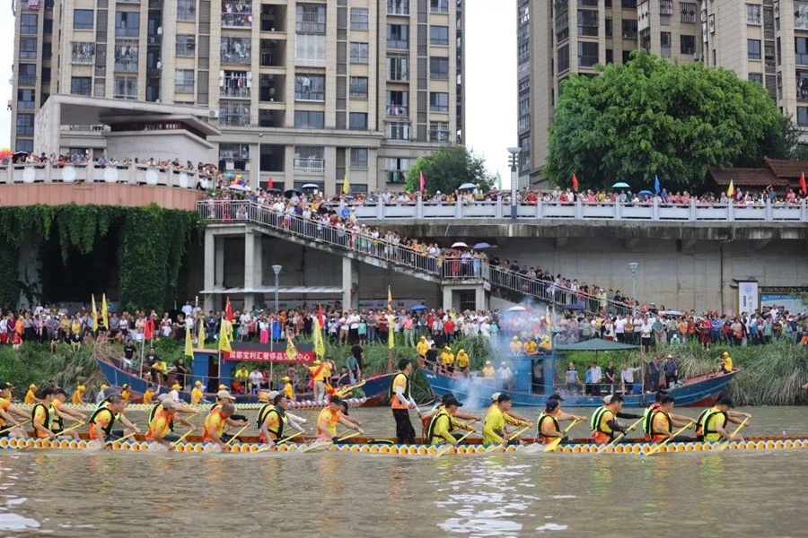 河岸两侧，上千名围观群众为龙舟健儿们加油助威。