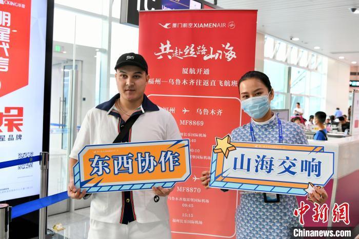 福州-乌鲁木齐往返直飞航班首飞旅客在登机口与厦门航空工作人员合影留念。　王东明 摄