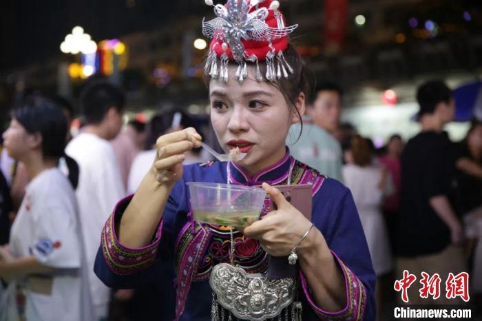 身着传统服饰的畲族姑娘品尝美食。福鼎市融媒体中心供图