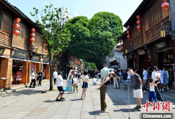 8月21日，游客在福州三坊七巷“爱心”树前合影。暑假期间，福州坊巷游受到各地游客的追捧。中新网记者 吕明 摄