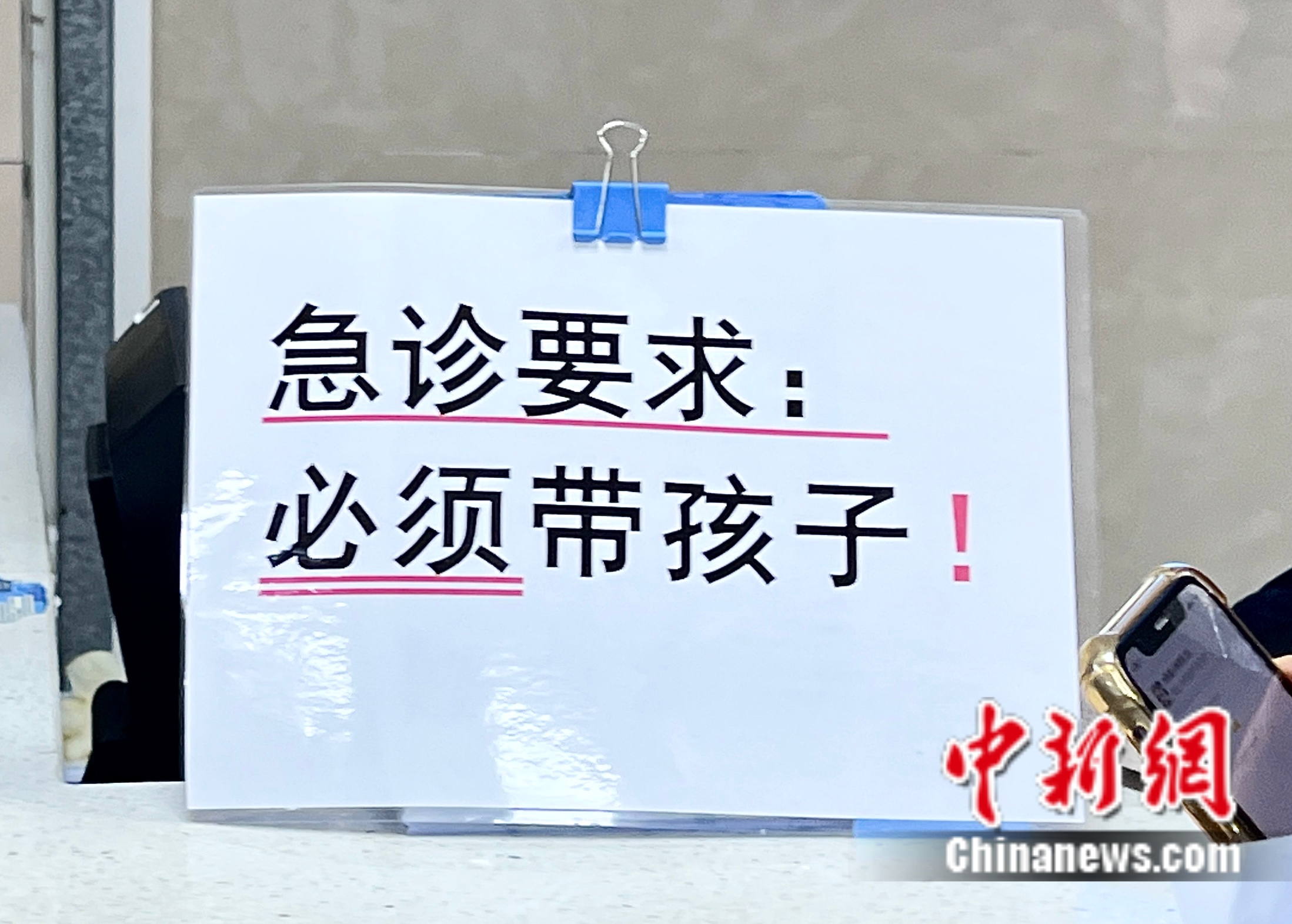 分诊台上有“急诊要求：必须带孩子”的提示语。邵萌 摄