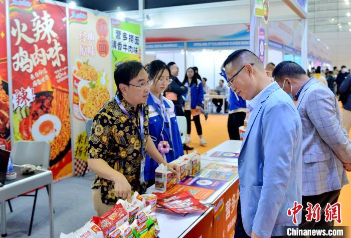 3月18日，第四届中国跨境电商交易会在福州开幕，来自印尼的陈兴大(左一)向观展者介绍营多捞面。中新社记者吕明摄
