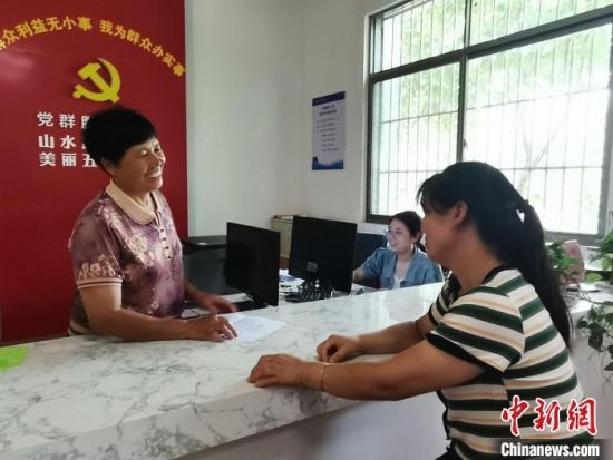 图为许光园(左一)与前来村部办事的村民交谈。　黄艳 摄