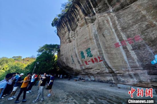8月5日，游客在福建连城冠豸山观看摩崖石刻。中新社记者 王东明 摄
