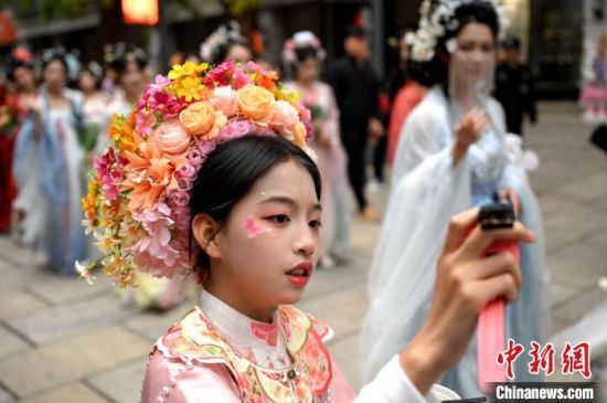 4月5日，身穿汉服的女子扮演的“十二花神”，在福州上下杭历史文化街区巡游、表演，带给游客一场春日里的国风浪漫。图为头戴簪花围的小朋友与“花神”合照。中新社记者 吕明 摄