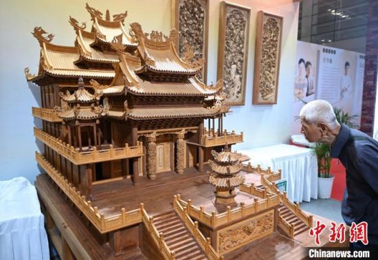 图为木雕作品吸引参观者。中新社记者 吕明 摄
