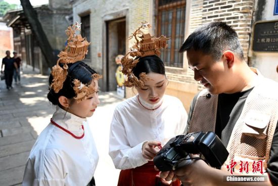 图为6月23日，游客郑榕晴（左）、顾语轩在福州上下杭历史文化街区旅拍，并观看照片。中新社记者 吕明 摄