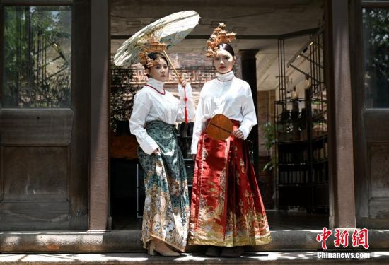 图为6月23日，游客郑榕晴（右）、顾语轩戴软木画头饰在福州上下杭历史文化街区旅拍。中新社记者 吕明 摄