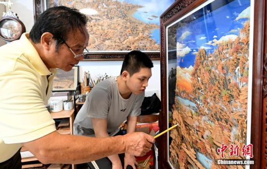 图为6月21日，陈国弦在福州的工作室为18岁的徒弟蒋涵威讲解软木画的相关知识。中新社记者 吕明 摄