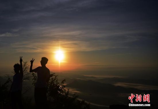 图为在大富村龙山观景台，游客与朝阳合影。中新社记者 张丽君 摄