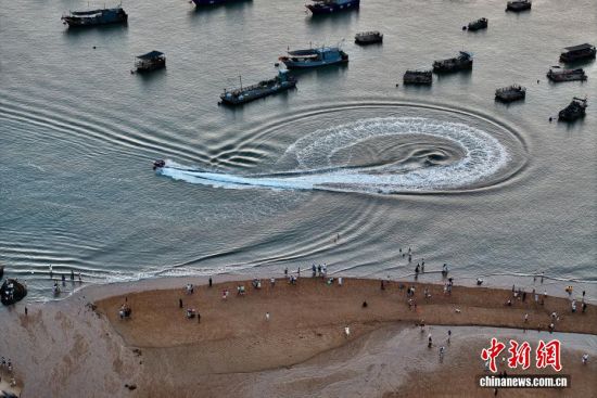 10月7日，游客在福建霞浦沙滩游玩。福建霞浦之滨凭借其旖旎的风光、独特的人文魅力，正吸引着越来越多的游客前来探寻。这里不仅是摄影爱好者的天堂，更是人们放松身心、感受大自然之美的好去处。(无人机照片)