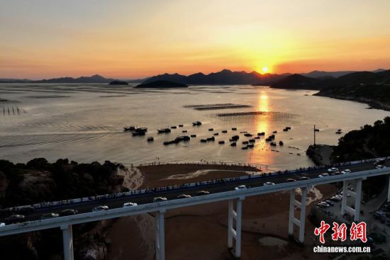 10月7日，游客在福建霞浦观看日落。福建霞浦之滨凭借其旖旎的风光、独特的人文魅力，正吸引着越来越多的游客前来探寻。这里不仅是摄影爱好者的天堂，更是人们放松身心、感受大自然之美的好去处。(无人机照片)