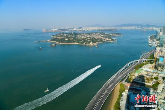 图为参赛选手在演武大桥赛段奔跑，远处是厦门著名景点鼓浪屿。中新社记者 王东明 摄