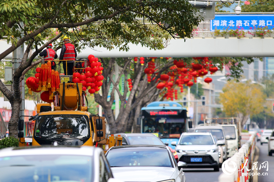 工人们在车流中登高作业挂灯笼。人民网记者 陈博摄