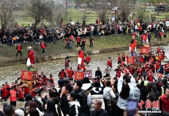 图为村民们抬着“古事”在水中逆行。中新社记者 张斌 摄