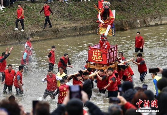 图为村民们抬着“古事”在水中逆行。中新社记者 张斌 摄