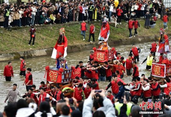 图为村民们抬着“古事”在水中逆行。中新社记者 张斌 摄